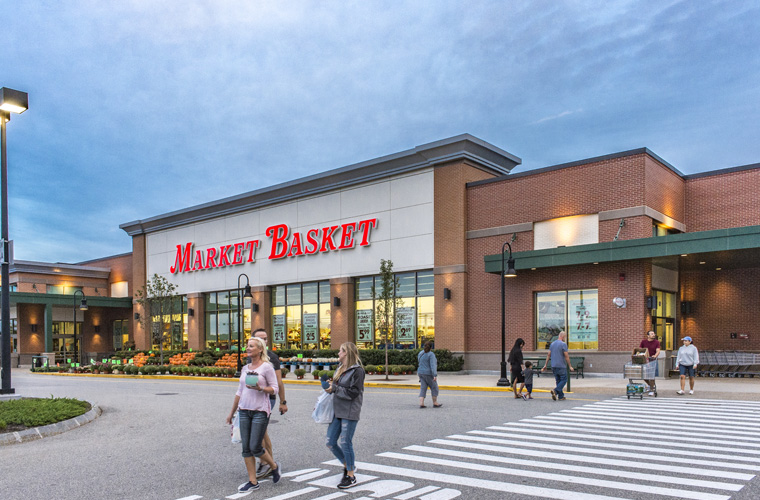 people walking through the crossing in front of market basket entrance